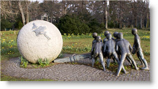 sculpture of figures pushing on sphere with a lever