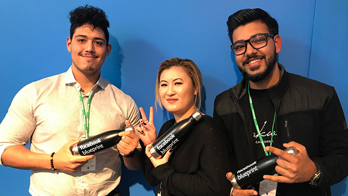 three students holding facebook thermos