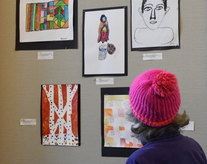 Older woman in pink hat looking at artwork