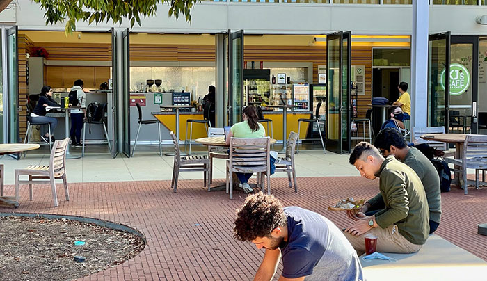 3 students sitting outside a cafe